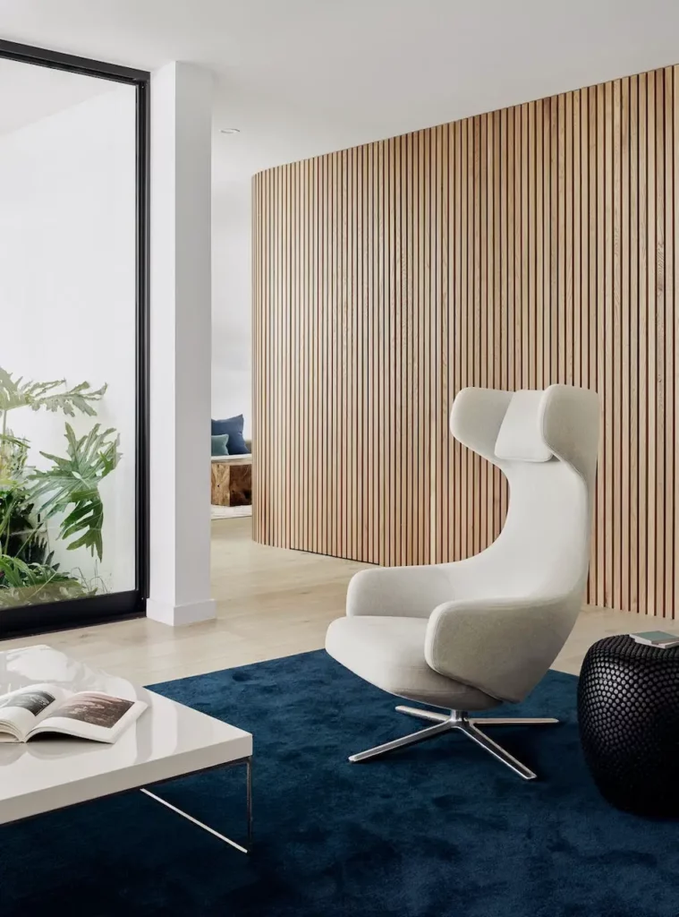 A modern living room with wooden walls and a blue rug is perfect for those seeking a cozy home.