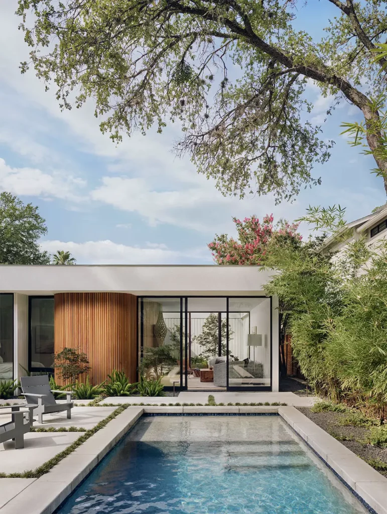 A contemporary house with a swimming pool and lounge chairs available for home buying.