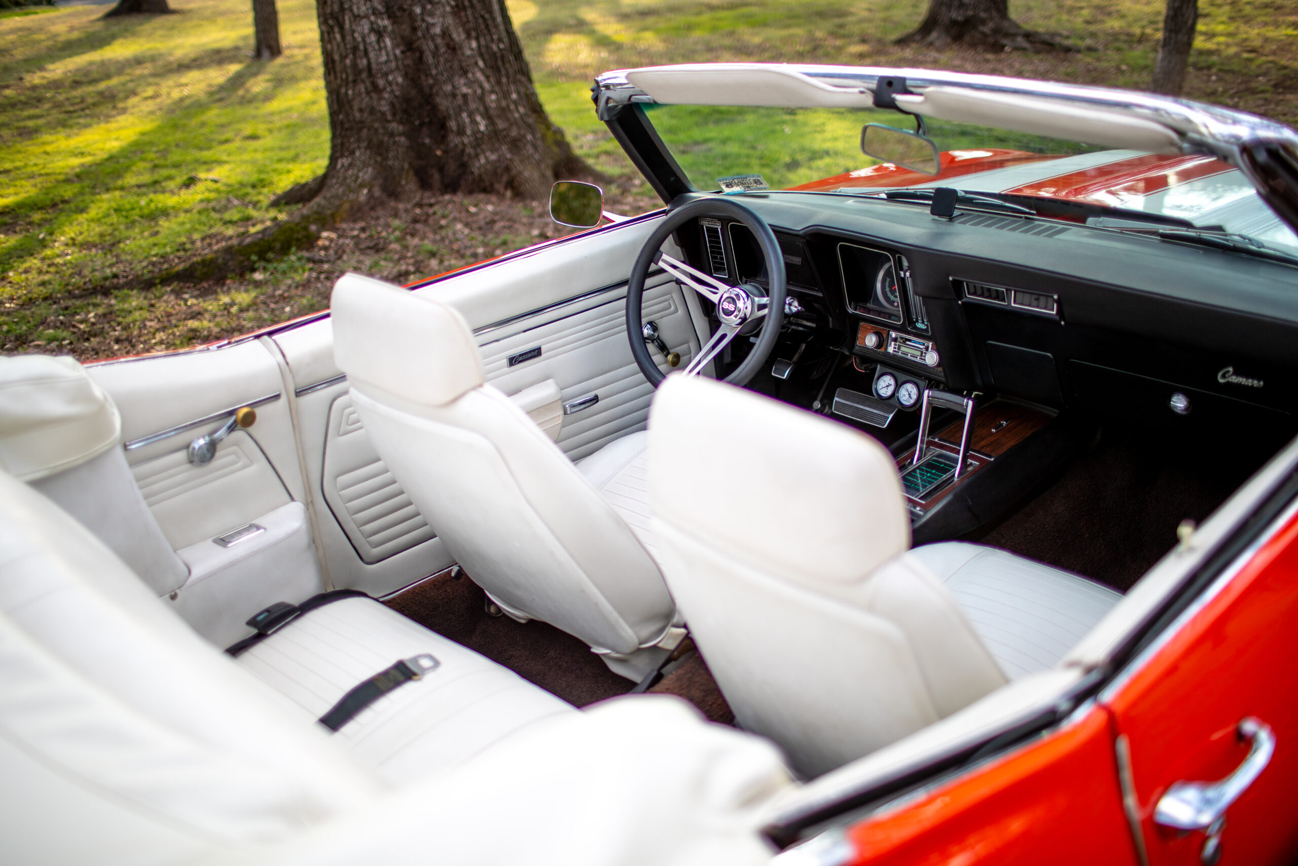 Interior view of a vintage convertible car with white leather seats and a classic dashboard design, ideal for real estate agents looking to impress clients.