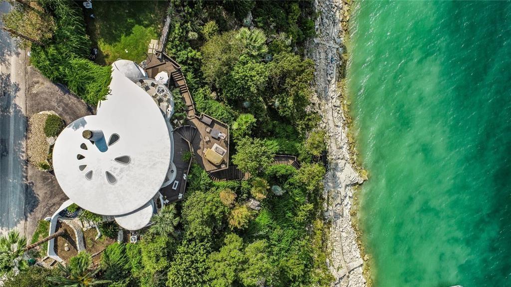 Aerial view of a white house by the ocean. Contact Austin Realtor for details.