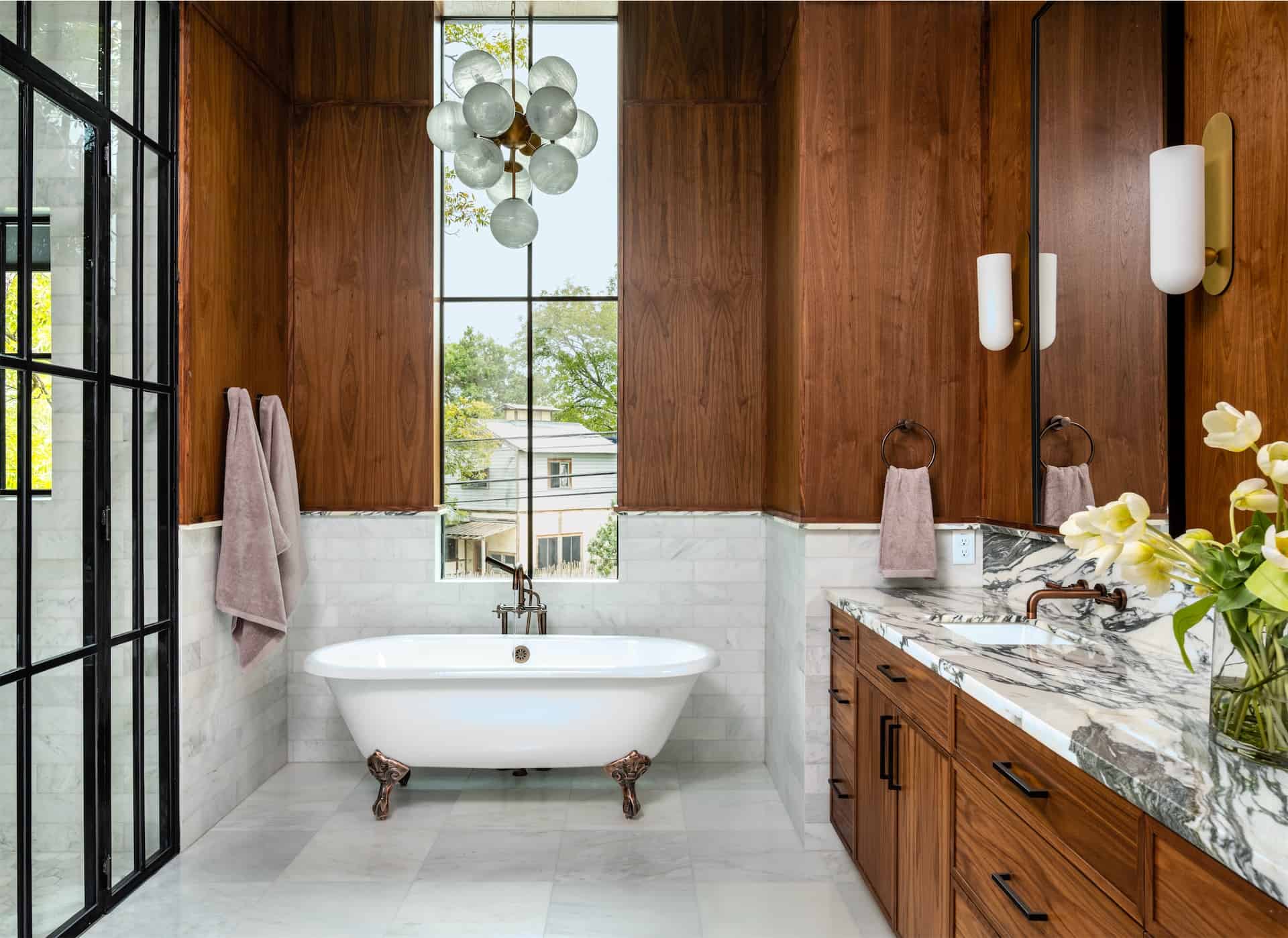 A bathroom with wood paneling and elegant marble counter tops is a luxurious feature of this real estate property.
