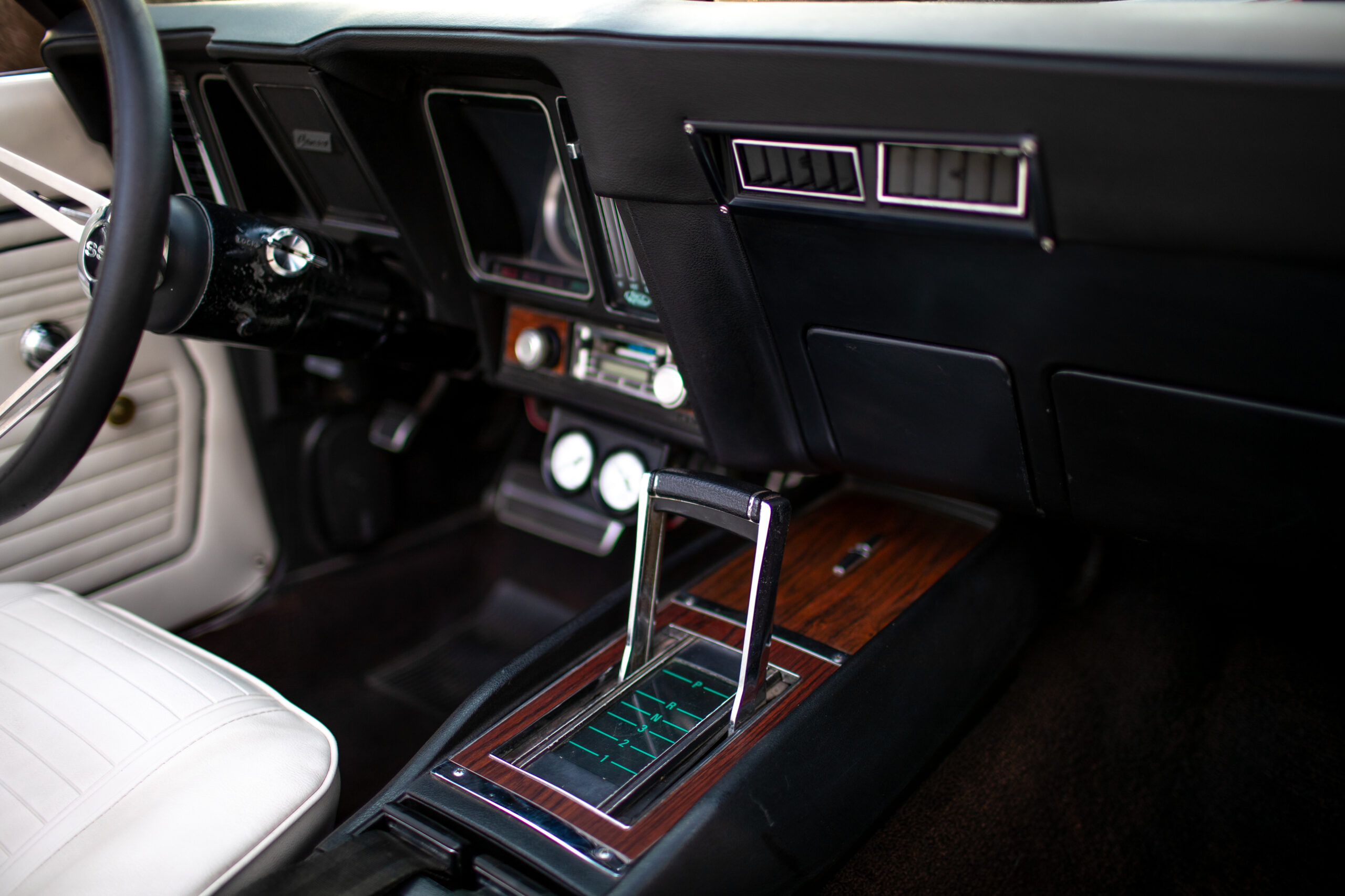 Interior view of a car showcasing the steering wheel, dashboard controls, and a center console featuring a vintage gear shift with wooden trim.