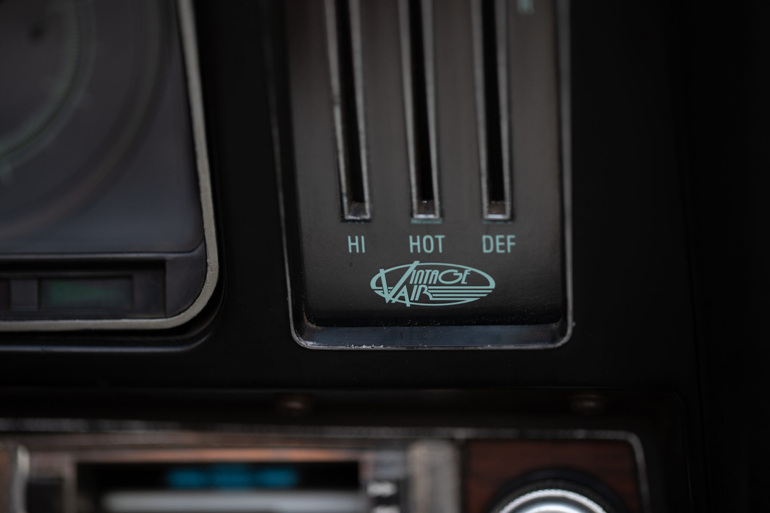 Close-up of a car's vintage climate control panel with options for "HI," "HOT," and "DEF," featuring the "Airtop Air" logo.